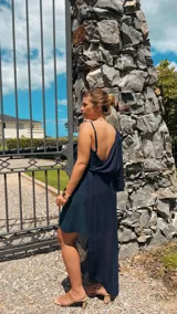 Vestido largo azul marino con un hombro descubierto, manga larga abullonada y falda irregular con sobrevestido de crepé.