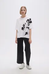 Remera blanca de corte holgado con estampado de flores negras.
