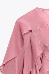 Blusa marrón de gasa con escote en V y manga larga abullonada. Presenta volantes en el mismo tejido y cierre frontal con botones.