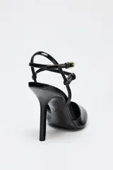 Zapato de tacón destalonado negro acharolado con tiras finas cruzadas ajustables con hebilla al tobillo y punta fina.