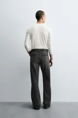 Pantalón de jean celeste de corte flare, con tiro medio, cinco bolsillos, cierre frontal con cremallera y botón, y bajo con acabado irregular.
