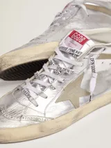 Zapatillas deportivas Golden Goose modelo Mid Star, de caña media, color plateado con detalles en dorado y beige. Presentan una estrella de gamuza en el lateral, perforaciones decorativas y cordones con logo estampado. Suela con efecto desgastado.