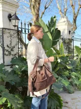 Bolso de mano tipo doctor bag color marrón, confeccionado en cuero con textura de efecto cocodrilo. Cuenta con doble asa superior, cierre metálico superior y bolsillos laterales externos.