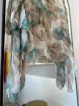 Blusa de seda italiana con estampado abstracto en tonos aqua, marrón y blanco. Tiene cuello redondo y corte asimétrico en el ruedo. Incluye musculosa interior.
