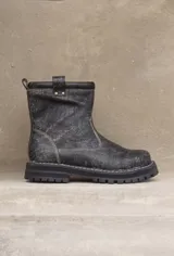 Botas cortas de cuero color gris gastado, con suela track y detalle de hebilla en la caña.