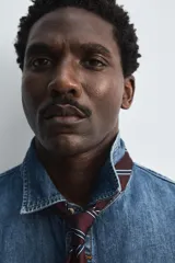 Camisa relaxed fit confeccionada en denim de algodón con cuello solapa, manga larga con puño abotonado, efecto lavado medio y cierre frontal con botones.
