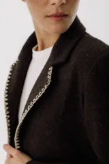 Blazer color camel de lana con solapas y cierre con botones. Presenta detalle de pespuntes blancos en los bordes.