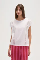 Remera blanca de algodón con apliques de encaje en los hombros, corte holgado y cuello redondo.