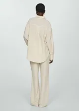 Camisa color crema de bambula, con cuello camisero, manga larga con puños abotonados, bolsillo de parche en la parte delantera, diseño oversize y cierre delantero con botones.