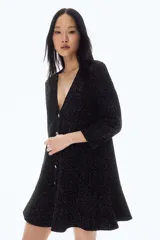 Vestido corto negro en tejido bouclé con hilos brillantes, escote en V, mangas tres cuartos y falda con vuelo.