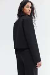 Pantalón cigarette tobillero negro con cintura estándar, cierre y pretina prolongada con corchete oculto. Piernas ajustadas con abertura corta en los bajos, bolsillos al bies y bolsillo de atrás decorativo. Pliegues adelante y atrás.