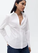 Camisa blanca entallada de algodón con cuello camisero y cierre frontal con botones.