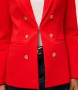 Blazer femenino color rojo, de corte estructurado, con cuello solapa, cierre frontal con botones dorados y bolsillos delanteros.