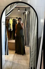 Vestido largo verde oliva de tela simil agamuzada, con escote halter, espalda baja y volados en cuello y cadera.