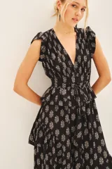 Vestido corto negro con estampado floral blanco, escote en V, volados en mangas y falda, cintura elastizada, frunces en hombros, tajo central y cierre lateral invisible.