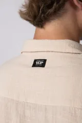 Camisa de lino color blanco, de manga corta, con cuello clásico y cierre frontal con botones.