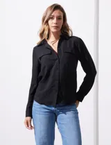 Camisa blanca de manga larga con cuello con solapa y abertura central con botones. Delantera con bolsillos aplicados.