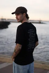 Remera negra de manga corta con cuello redondo y corte holgado. Estampa en la espalda con los títulos de canciones de la banda británica Oasis.