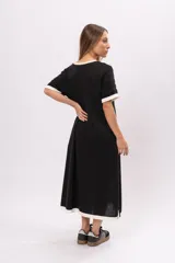 Vestido remerón largo de manga corta color negro, con cuello y puños blancos, y aberturas laterales.