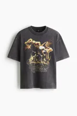 Remera gris con efecto lavado, corte holgado, cuello redondo y estampado de un águila, cactus y texto "Rodeo Sunset".