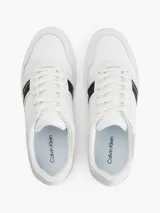 Zapatillas urbanas Calvin Klein color blanco con detalles en cuero sintético y gamuza color crema. Presentan una franja lateral negra con el logo de la marca.