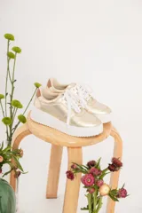 Championes urbanos dorados con cordones blancos y suela blanca con plataforma.