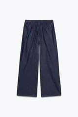 Pantalón de jean azul oscuro, de tiro alto y pierna ancha, con cintura elástica ajustable con cordones y bolsillos delanteros.