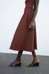 Falda midi marrón con textura, de tiro alto y cierre lateral con cremallera oculta.