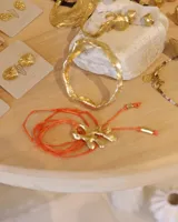 Collar con dije de bronce macizo con forma orgánica o de coral, suspendido de un hilo de seda natural color naranja.