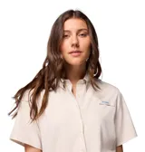 Camisa de manga corta color beige claro, con cuello abotonado y cierre frontal con botones. Tiene dos bolsillos en el pecho con cierre de velcro y logo de la marca en el bolsillo izquierdo.