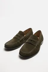 Mocasín color marrón de cuero con acabado serraje, antifaz, horma redonda y suela con ligero tacón.