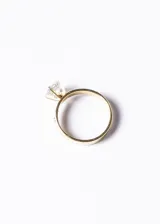 Anillo dorado de acero quirúrgico con circonia central y pequeñas circonias engarzadas en el aro.