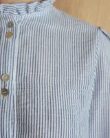 Camisa blanca de mangas 3/4 con cuello mao y botones frontales.