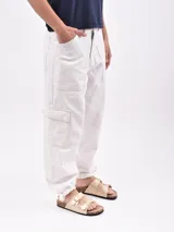Pantalón jean náutico color blanco hueso, de corte recto, con bolsillos laterales tipo cargo y tobillos ajustados con elástico.