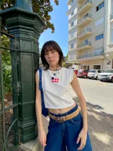 Remera blanca sin mangas de algodón con un bolsillo en el pecho con la bandera de Uruguay.