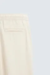 Pantalón verde oscuro de algodón con textura, corte recto, cintura elástica ajustable con cordón, bolsillos laterales y traseros de vivo.