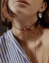 Gargantilla marrón de cuero sintético con dije circular con strass y lazos para atar.