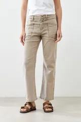 Pantalón de jean color beige, de corte recto, con bolsillos laterales y traseros. Se ajusta a la cintura con cinturón de cuero marrón.