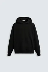 Sudadera con capucha negra, corte relaxed fit, confeccionada en tejido de algodón con interior rizo, manga larga, bolsillo frontal tipo canguro y terminaciones en rib.