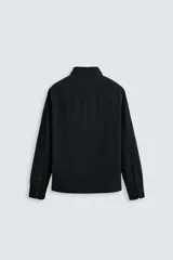 Camisa azul de algodón con textura chambray, corte regular fit, cuello abotonado, manga larga con puños abotonados, bolsillo de parche en el pecho y cierre frontal con botones.