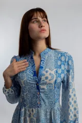 Vestido midi de corte amplio con estampado floral en tonos azules y blancos. Tiene cuello mao con botones y mangas largas abullonadas.