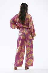 Pantalón de mujer con estampado de flores grandes color naranja sobre fondo fucsia. El pantalón es de corte palazzo y tiro alto.