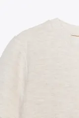 Remera de punto color crema, de corte recto, cuello redondo y manga corta.