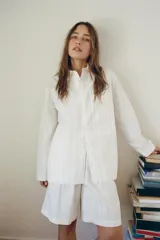 Camisa tipo pijamera de algodón a rayas verticales grises sobre fondo blanco, con cuello solapa, manga larga, bolsillos de plastrón y cierre frontal con botones.