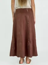 Pollera larga negra de corte amplio, con costuras verticales que simulan pliegues y terminaciones deshilachadas. Se combina con una musculosa negra de escote redondeado.