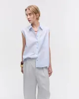 Camisa celeste a rayas verticales, sin mangas, de voile de algodón liviano, con cuello camisero, cartera con botones de nácar, bolsillo plaqué en delantero y ruedo escalonado.