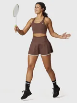 Falda deportiva tipo skort color chocolate con borde inferior en contraste blanco. Confeccionada en tejido técnico con short integrado y bolsillo oculto.