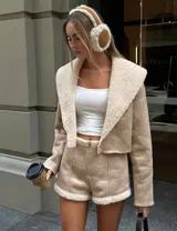Conjunto color beige compuesto por chaqueta corta con cuello de piel sintética y short con cierre frontal.