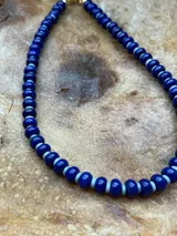 Collar corto de cuentas redondas de vidrio color azul con detalles blancos, engarzadas en hilo de acero con cierre de mosquetón dorado.