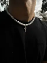 Collar de perlas blancas con dije de cruz plateada con incrustaciones de strass.